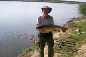 Мушкарац држи рибу на обали језера